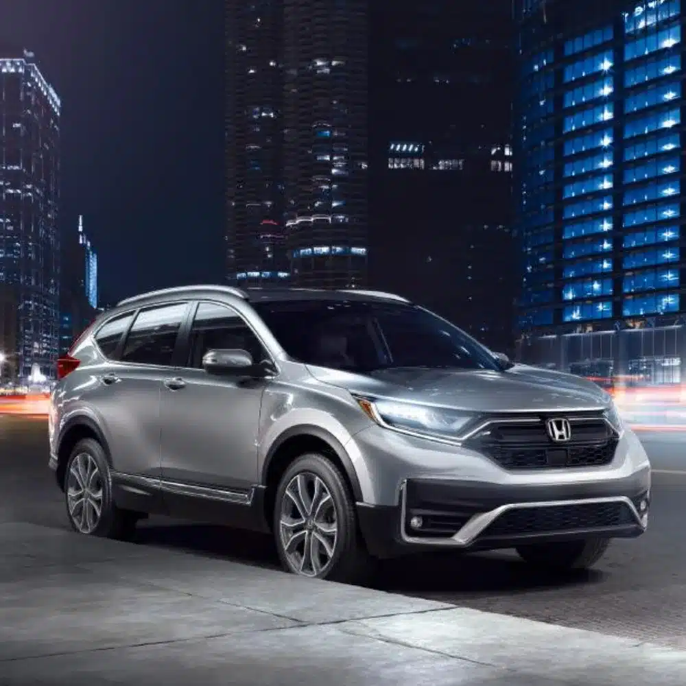 A new Honda CR-V parked outside a modern dealership building in scenic Vermont.