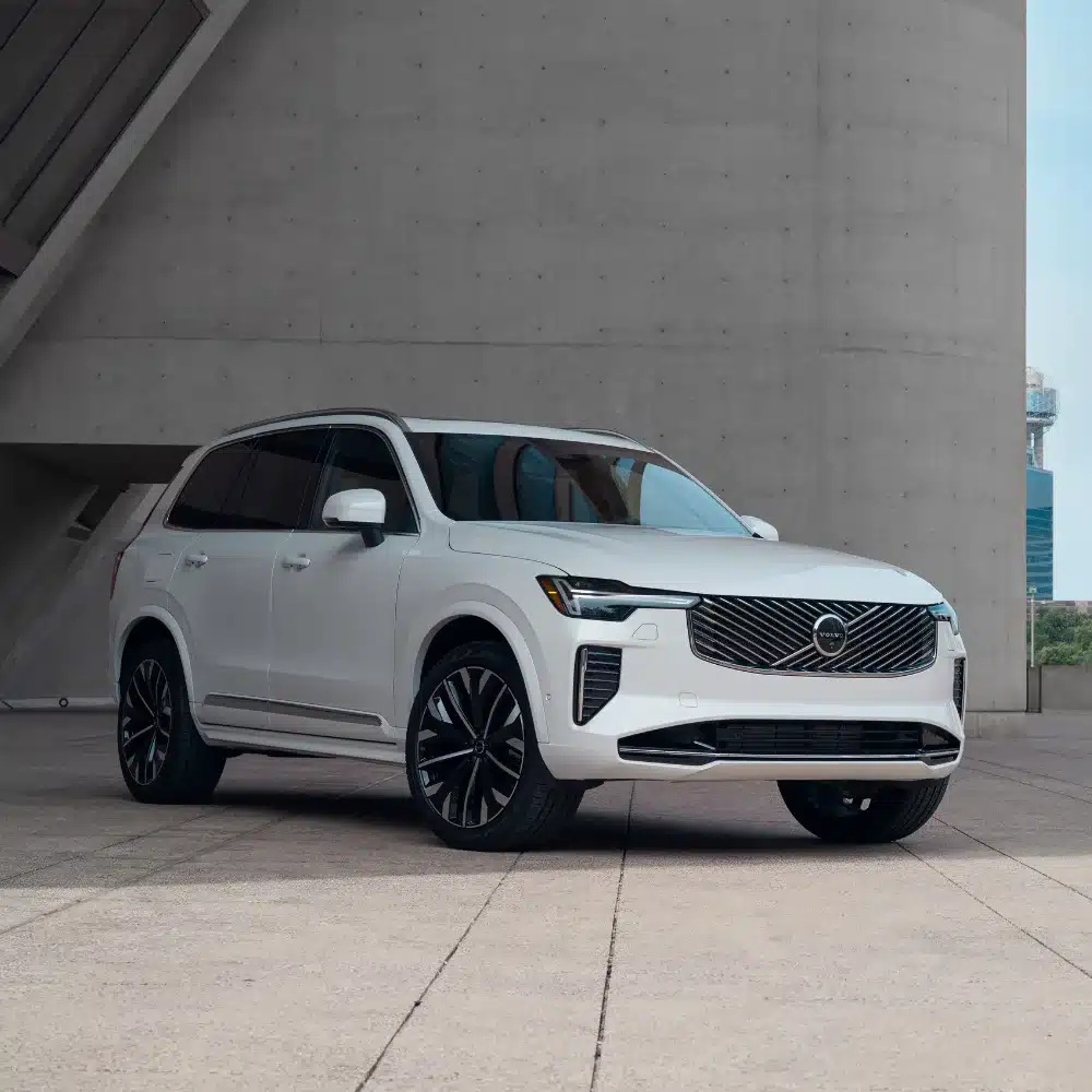 A sleek Volvo XC90 Recharge model parked outdoors, highlighting its plug-in hybrid design.