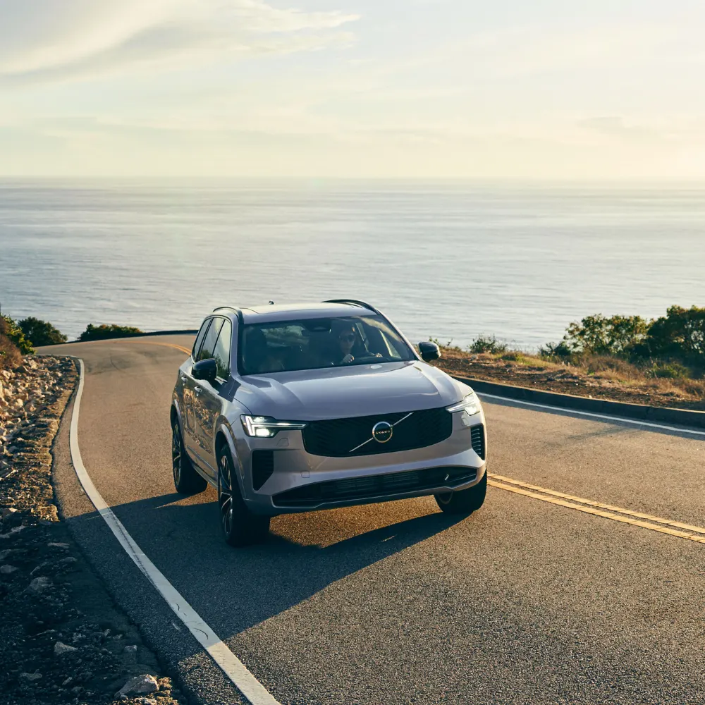 A customer test drives a pre-owned Volvo, assisted by a friendly dealership associate.